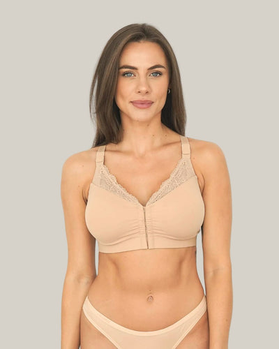 Woman wearing a beige bra and panties set on a plain background