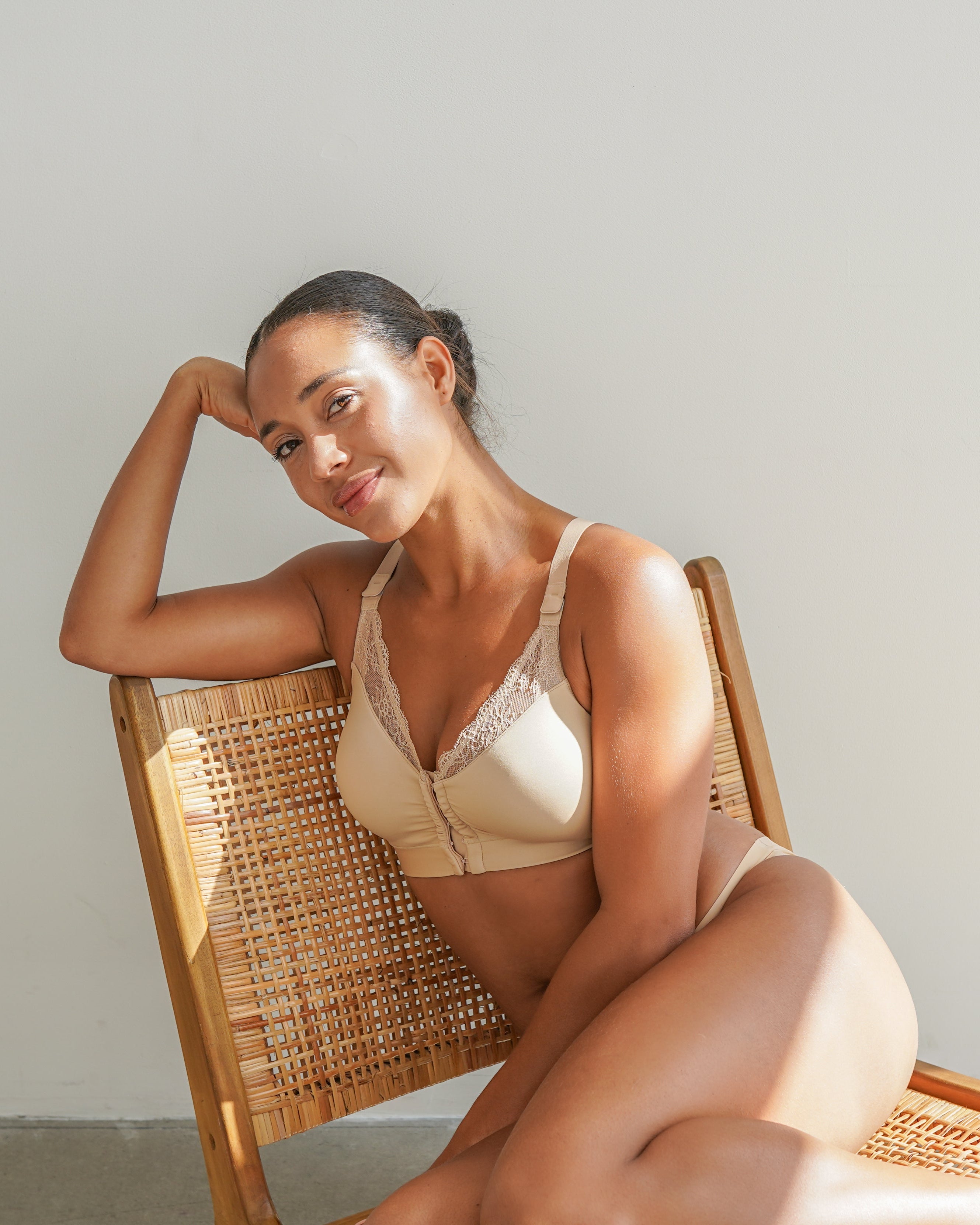 Woman sitting on a wicker chair wearing a beige bikini against a plain background