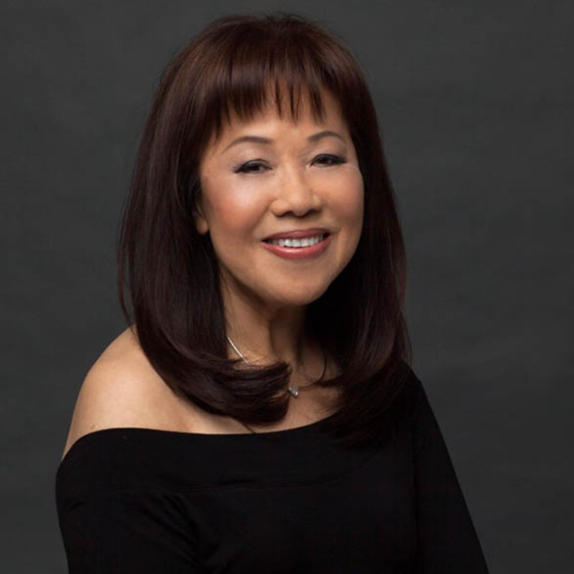 Woman with shoulder-length dark hair against a gray background