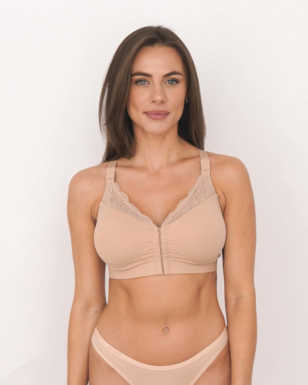 Woman wearing a beige bra and panties set on a plain background
