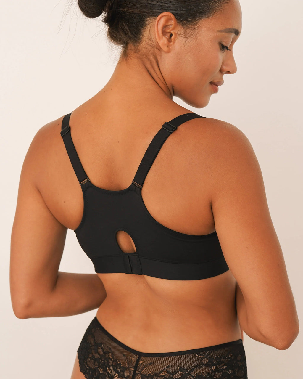 Woman wearing a black sports bra and underwear set on a beige background