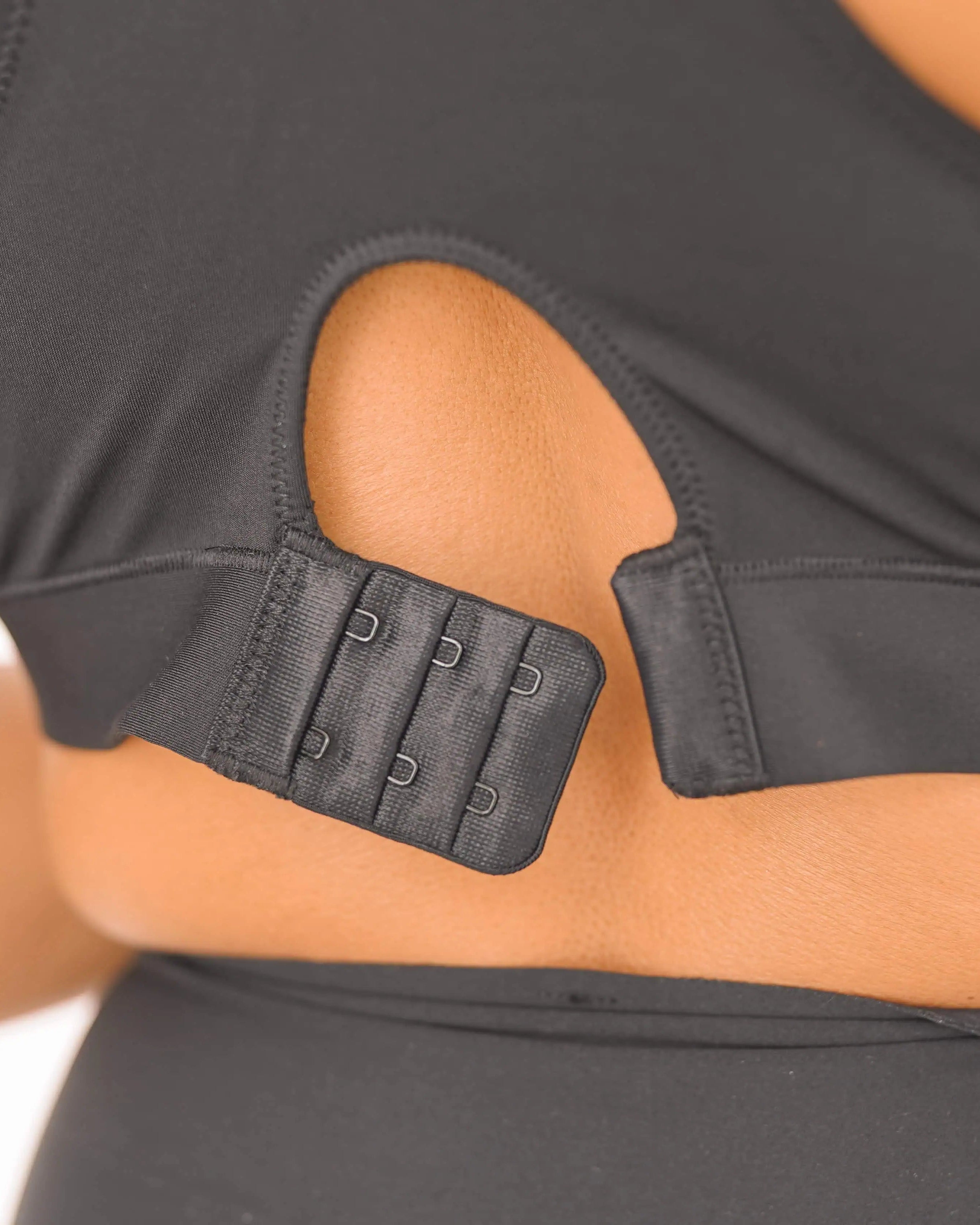 Person wearing a black sports bra with built-in support straps on a plain background
