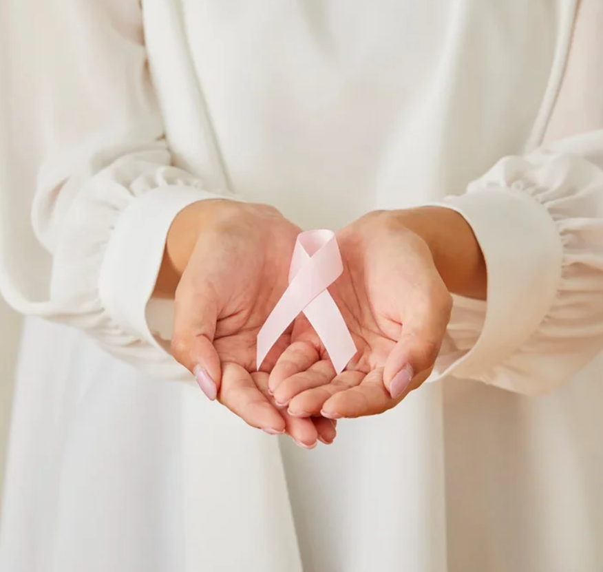 Hands holding a pink ribbon against a white background