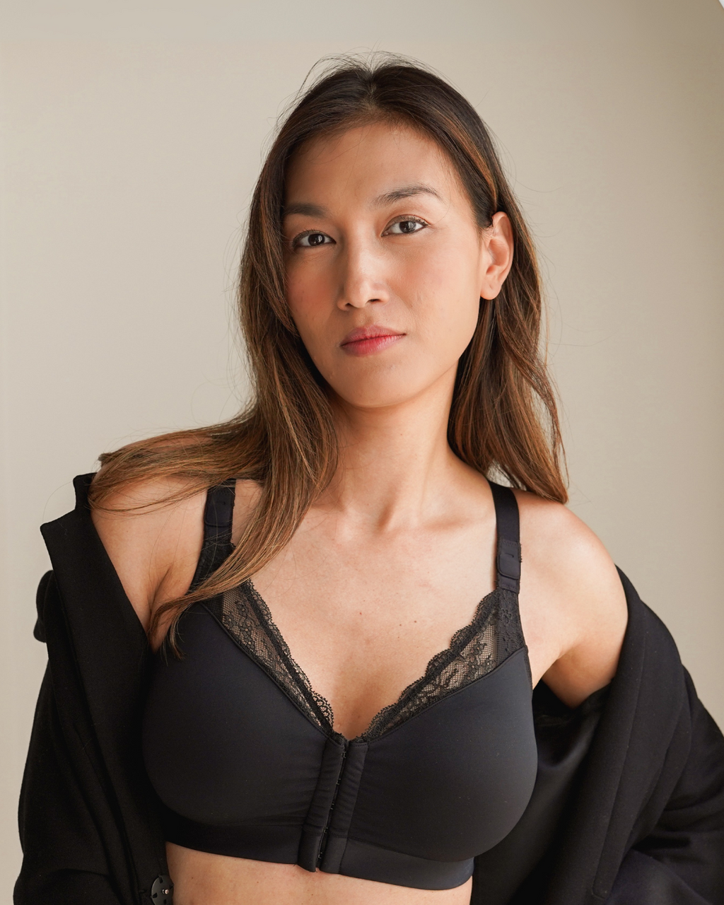Woman wearing black lace post surgical compression bra with front closure and lace trim