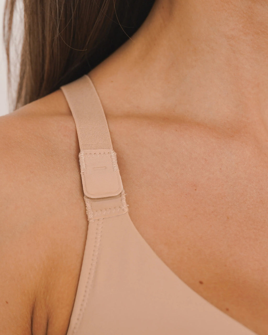 Close-up of a beige tank top worn by a person on a plain background