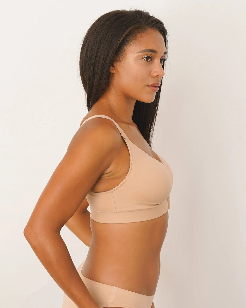 Woman wearing a beige bra and panties set on a white background